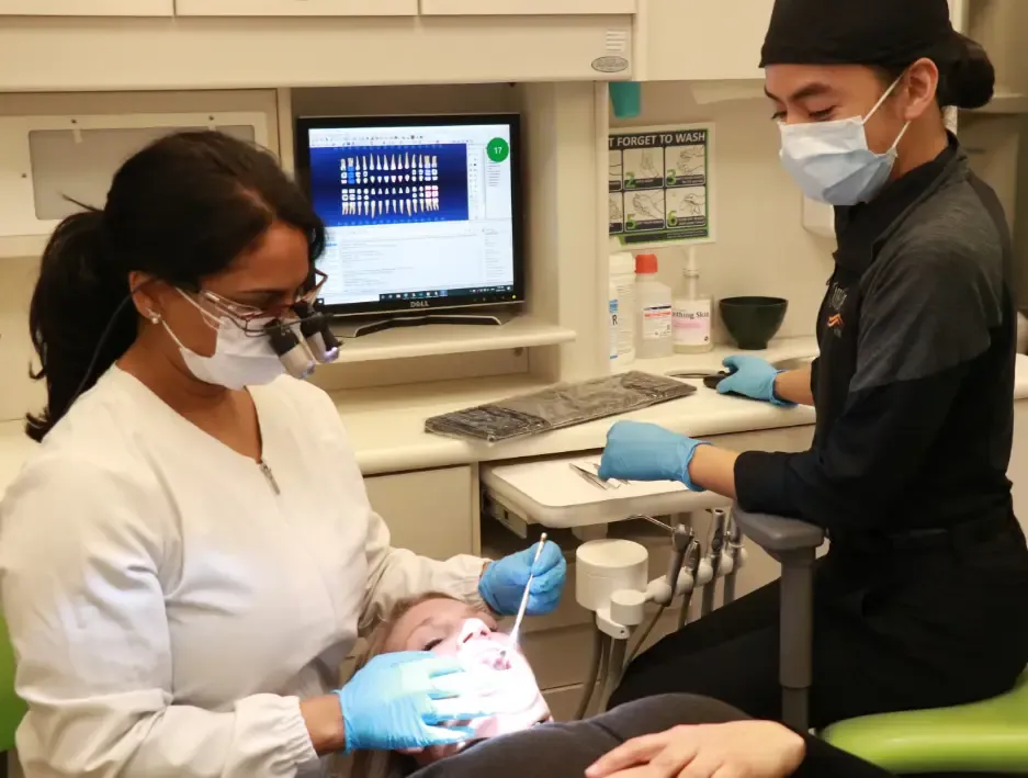 Dentist and dental assistant treating a patient in the treatment room