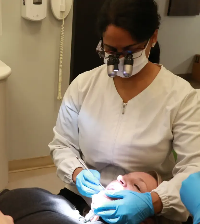 Dentist wearing magnifying loupes treating a patient