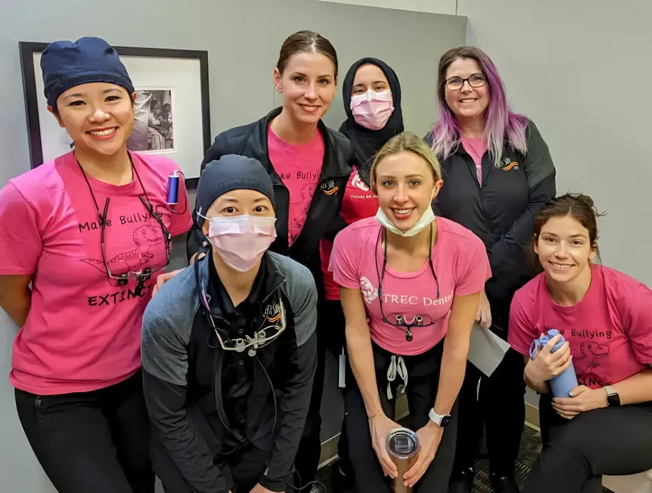 Team members in pink shirts smiling together